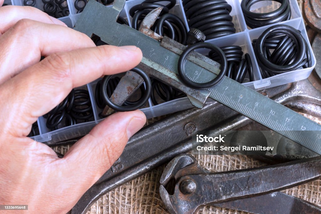A man is holding an old measuring instrument in his hands. Measuring the diameter of the rubber ring with a caliper. A man is holding an old measuring instrument in his hands. Caliper Stock Photo