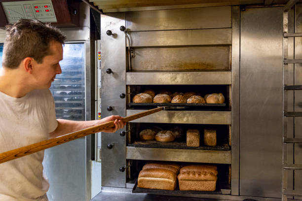 istock Baker taking bread out of oven 1333704478