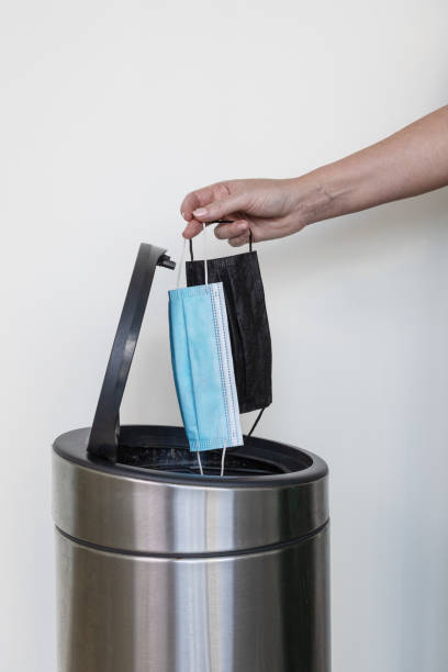 istock A woman's hand throwing out medical face masks in a rubbish bin 1333704579