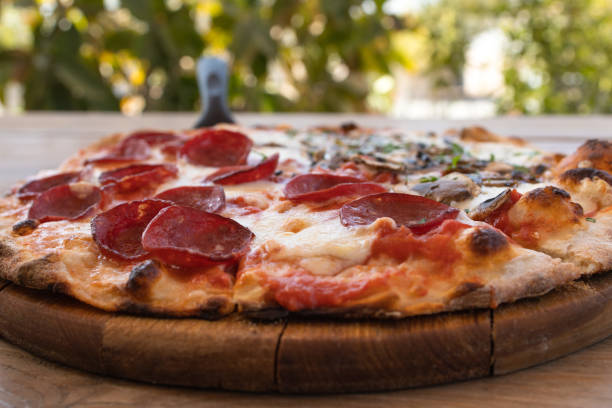 istock A pizza on a wooden board in a table outdoors 1333704625