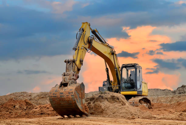istock Excavator working on earthmoving at open pit mining on sunset background. Backhoe digs sand and gravel in quarry. Heavy construction equipment during excavation at construction site 1333706875