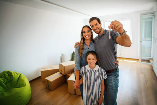 Family moving into a new apartment. Family moving in a new apartment. They are standing and holding a house key, smiling and looking at camera. happy family with key of their new house stock pictures, royalty-free photos & images