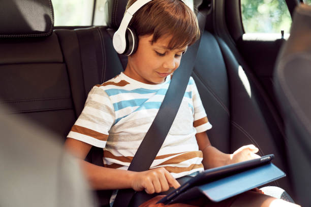 niño sentado con una tableta digital en el coche - seat belt audio fotografías e imágenes de stock