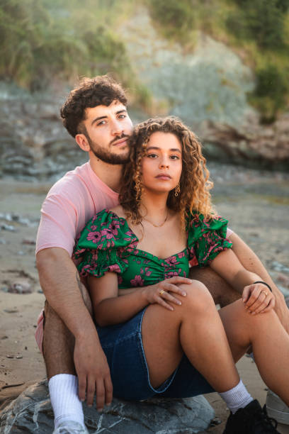 encantadora pareja heterosexual en una playa rocosa abrazándose y besándose en el país vasco. - honeymoon beach couple heterosexual couple fotografías e imágenes de stock
