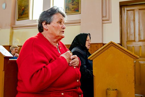 Ivanovo, Vojvodina, Serbia - April 17, 2016: Female believers are praying with their priest at Sunday morning in old and small Catholic Church.