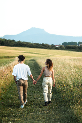 Lovely heterosexual couple in a grass field walking and kissing