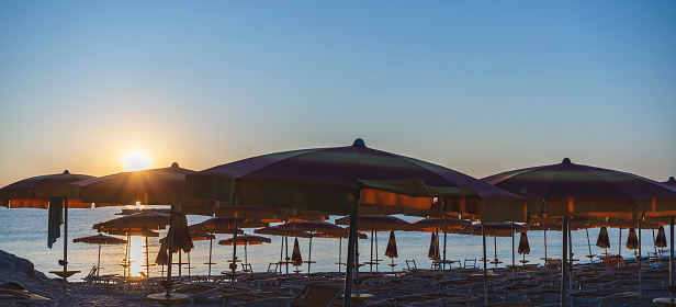 Bathhouse with beach umbrellas at dawn, clear sky