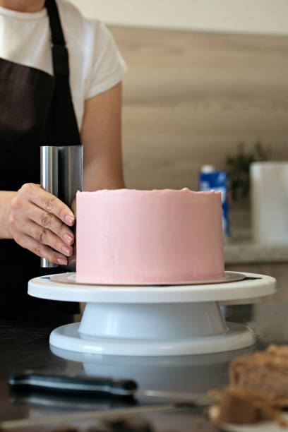 istock Woman pastry chef making chocolate cake with pink cream, close-up. Cake making process, Selective focus 1333714821