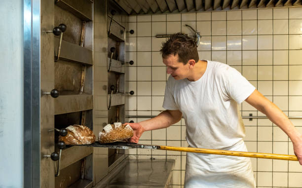 istock Baker taking bread out of oven 1333714871