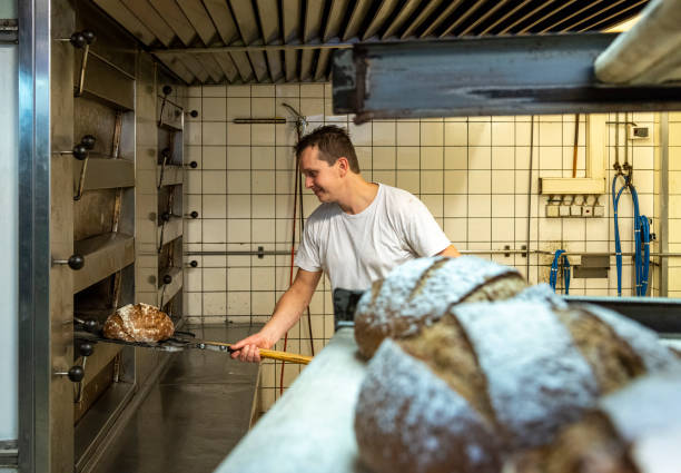 istock Baker taking bread out of oven 1333714967
