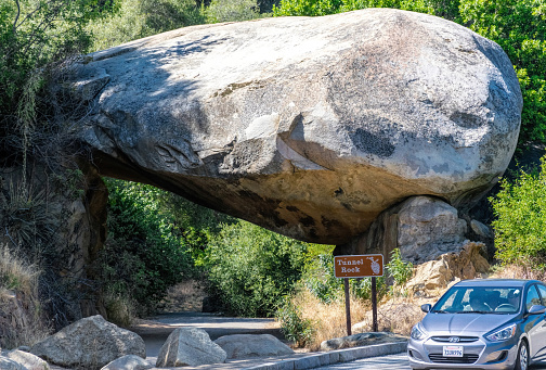 Three rivers, California, USA - June 14, 2019: giant natural stone arch Tunnel rock and a touring car near the entrance to Sequoia National Park in California, USA. Summer travel to the natural attractions of the American Southwest