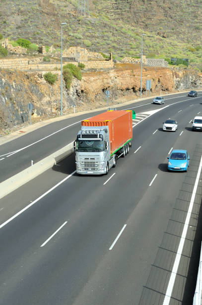 istock Truck transporting a shipping container among highway traffic. 1333717894
