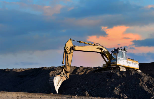 istock Excavator working on earthmoving at open pit mining on sunset background. Backhoe digs sand and gravel in quarry. Heavy construction equipment during excavation at construction site 1333720188