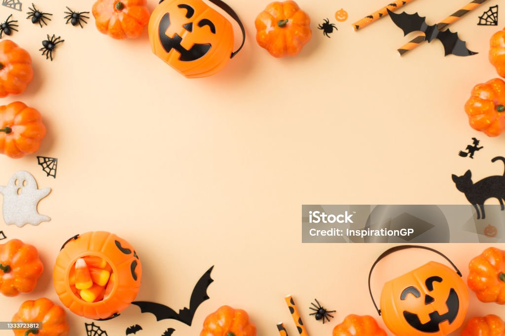 Vista superior foto de halloween decoraciones cestas de calabaza pajas de maíz caramelo pajas araña tela murciélagos fantasma y siluetas de gato negro sobre fondo beige aislado con copyspace en el medio - Foto de stock de Halloween libre de derechos