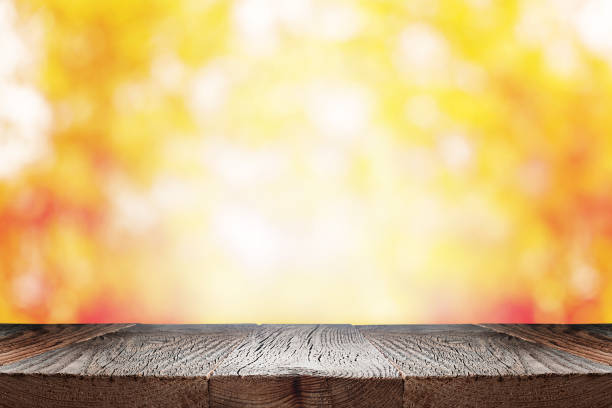 Empty wooden table over blurred autumn foliage background. Empty wooden table over blurred autumn foliage background. Fall background with empty space for product display. fall picnic table stock pictures, royalty-free photos & images