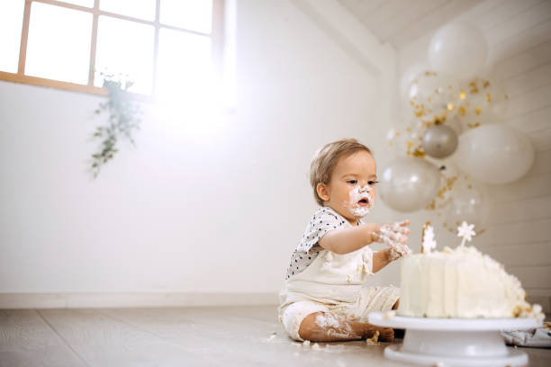 istock Cute messy little boy with cake on his first birthday party 1333725346