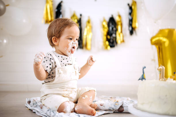 istock Cute messy little boy with cake on his first birthday party 1333725357