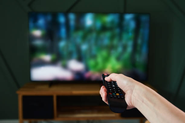 istock Woman switch channels on TV set with remote control. 1333727516