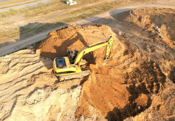 Excavator dig trench in ground at construction site. Foundation pit for a building. Excavator dig trench in ground at construction site. Foundation pit for a building. Earth-moving heavy equipment. Arial view of the earthwork. earthwork stock pictures, royalty-free photos & images