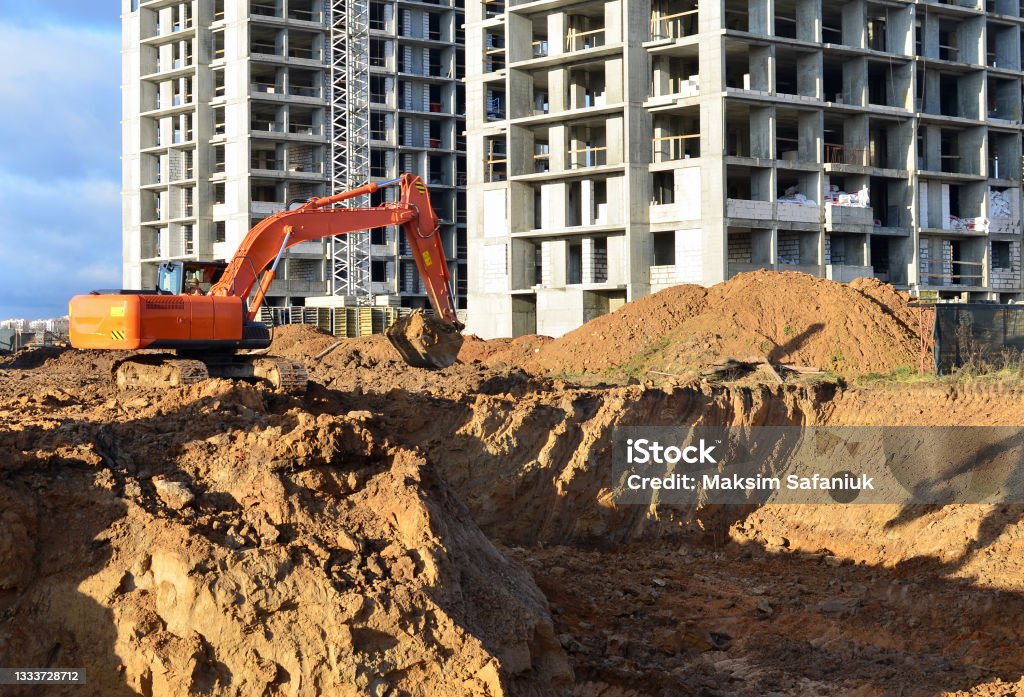 Excavator digging foundation at construction site. Heavy machinery for groungwork. House Construction Project Working. Earthwork Stock Photo