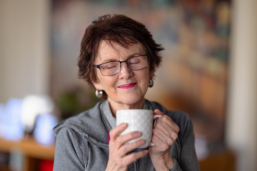 Happy senior woman enjoying a coffee break.
