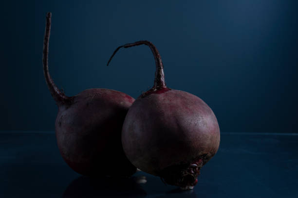 a pair of red beets on a black background minimalistic still life