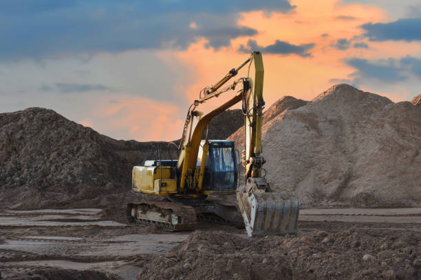 istock Excavator working on earthmoving at open pit mining on sunset background. Backhoe digs sand and gravel in quarry. Heavy construction equipment during excavation at construction site 1333733930