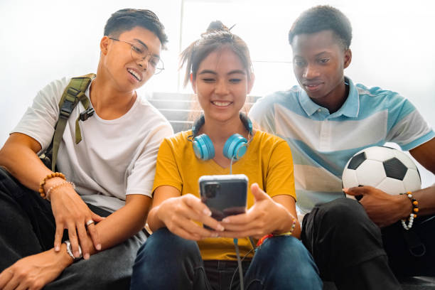 Multiracial group of teen high school classmates sit on stairs looking at teenage girl cell phone. Multiracial group of teen high school classmates sit on stairs looking at teenage girl cell phone. Back to school concept. Technology addiction concept. back to school teens stock pictures, royalty-free photos & images