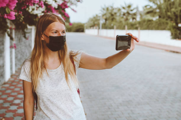 istock Coronavirus face mask protection woman taking selfie using smart phone covid-19 quarantine pandemic lockdown new normal lifestyle city life 1333736056