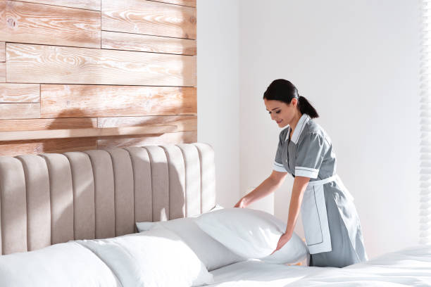 istock Young chambermaid making bed in hotel room. Space for text 1333736350