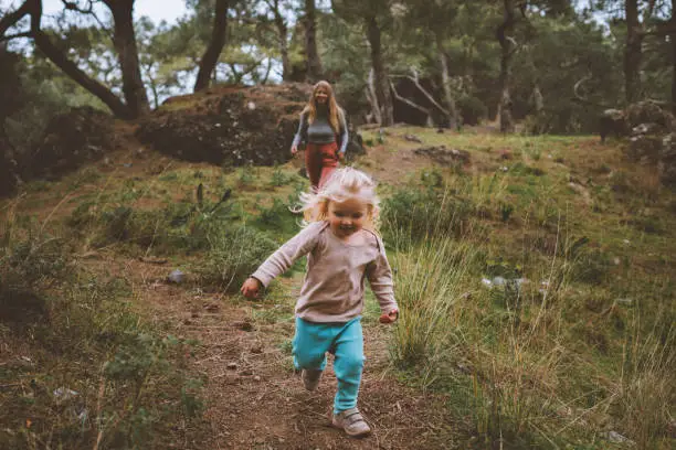 Photo of Child girl running in forest family vacations travel lifestyle 2 years old baby walking with mother outdoor happy emotions
