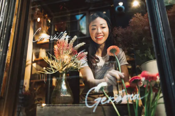 Asian young florist working on the arrangement of flowers for her shop.