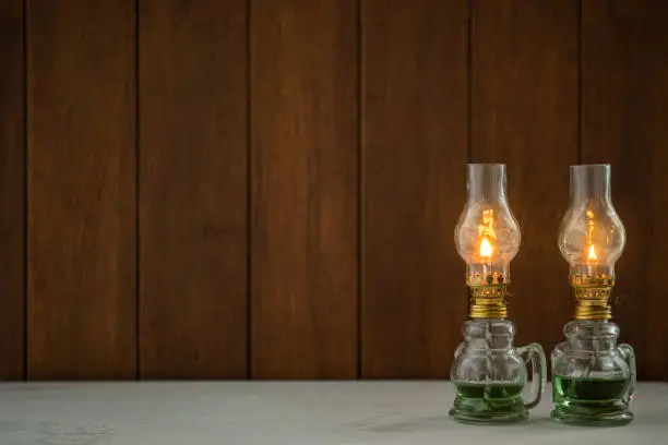 There is a vintage oil lamp on the table. The background is a wooden board.