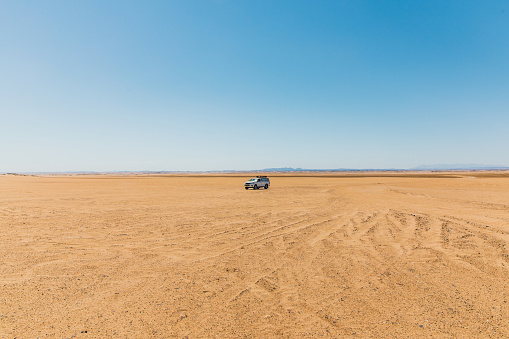 View of the white car with roof top tent at the warm sand during sunny day at Namib-Naukluft national park, Southern Africa