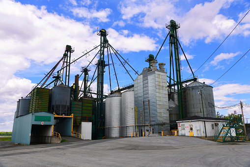 Low angle view of a soy crushing facility  in a farm area of Quebec against a white clouded blue sky