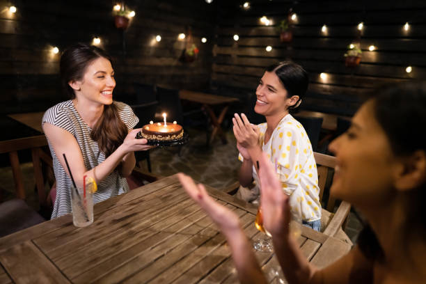 istock Happy girlfriends surprising their friend with birthday cake 1333744038