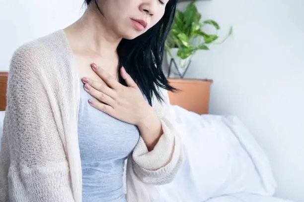 Photo of Asian woman hand holding chest pain, difficulty to breathe