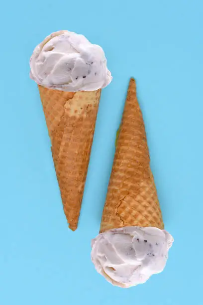 Two Chocolate Chip Ice Cream Cones on a blue background. Flat lay minimalist styling.