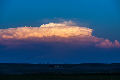 Suspended sunset: decaying supercell thunderstorm clouds catching the last rays of the setting sun; it appears suspended as the foreground is already in deep shadow, Kansas