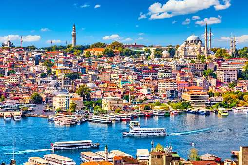 Touristic sightseeing ships in Golden Horn bay of Istanbul and mosque with Sultanahmet district against blue sky and clouds. Istanbul, Turkey during sunny summer day