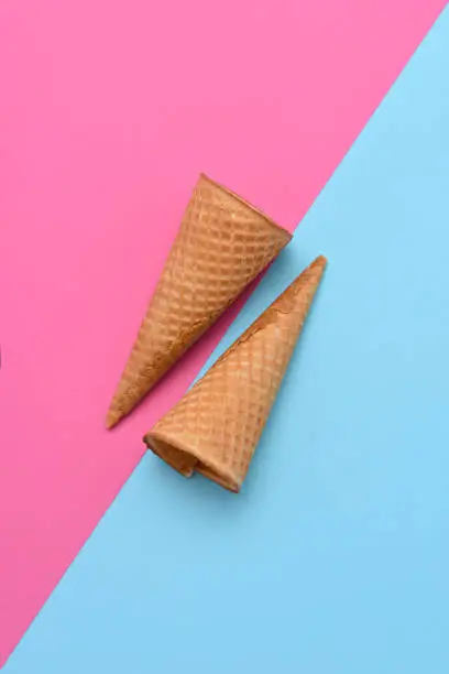 Two Ice Cream Cones on a blue and pink background. Flat lay minimalist styling. Background colors are an a 45 degree angle