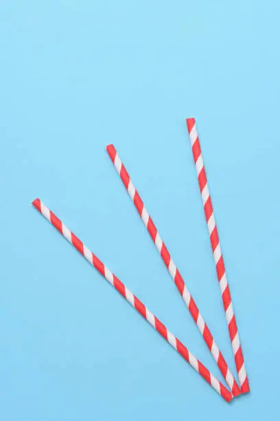 Red striped drinking straws on a pastel blue background. top view flat lay minimalism styling.