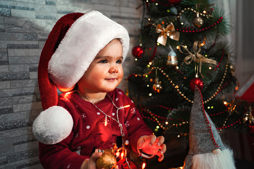 Baby girl in a red hat of Santa Claus in a Christmas decorations