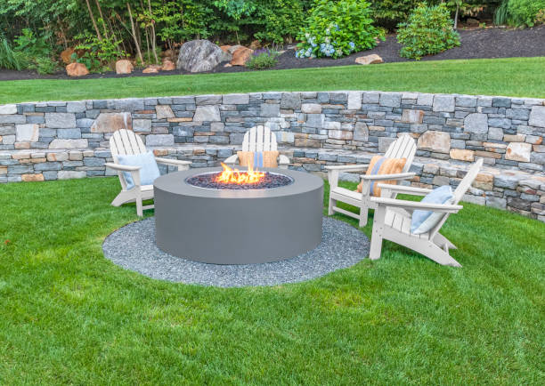 Adirondack chairs around fire pit Adirondack chairs around fire pit with stone wall and lush green grass. stone wall stock pictures, royalty-free photos & images