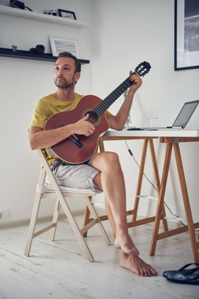 istock Man playing acoustic guitar at home. 1333759198