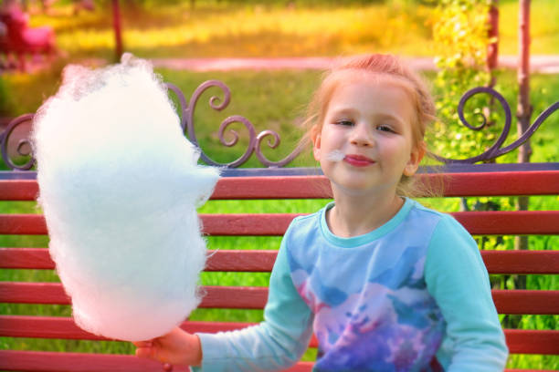 Child girl eating cotton candy, autumn time Child girl eating cotton candy, autumn time child cotton candy stock pictures, royalty-free photos & images