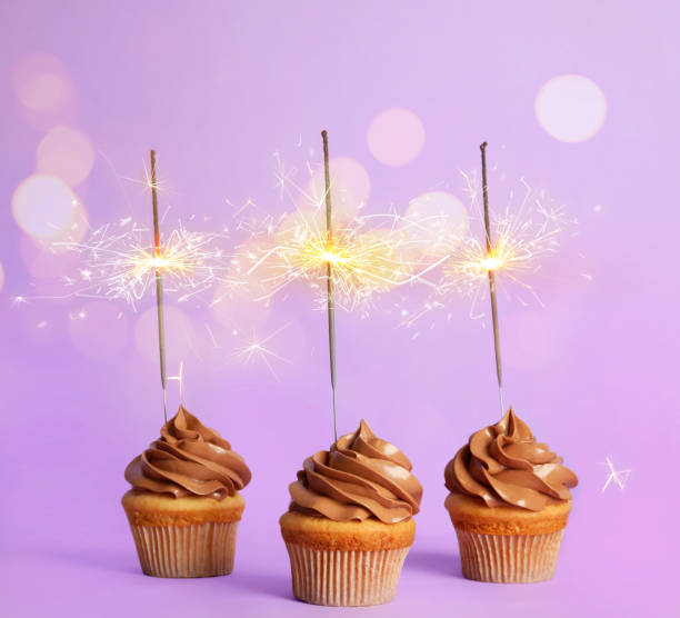 istock Birthday cupcakes with sparklers on violet background 1333761969