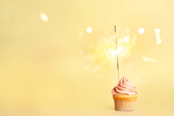 istock Birthday cupcake with sparkler on light yellow background. Space for text 1333762608