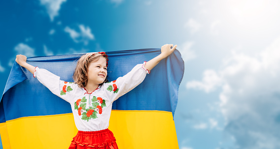 Niña ucraniana en camisa bordada vyshyvanka con bandera amarilla y azul de Ucrania en el campo. photo