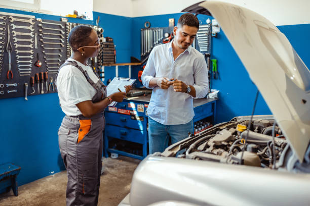 istock Client young man with female car mechanic in blue uniform standing with some documents in car service 1333765669